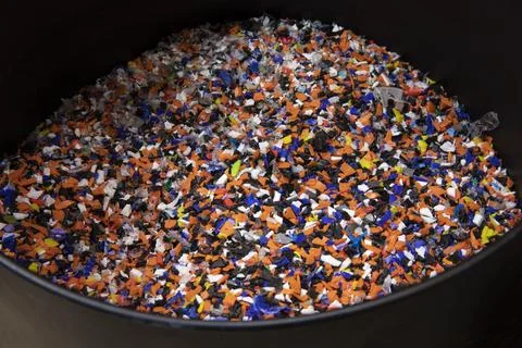 Plastic pellets made of multicolored recycled bottle caps in a black tub 写真素材