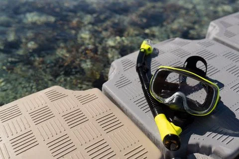 A plastic pier in the sea features a diving mask and snorkel. Stock Photos