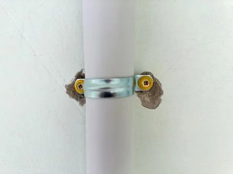 Plastic pipe fixed to the wall with metal pipe clamp Stockfoto's