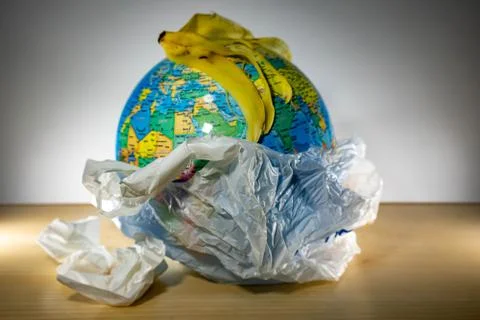Plastic with planet earth inside and some garbage like paper and banana lefto Stock Photos