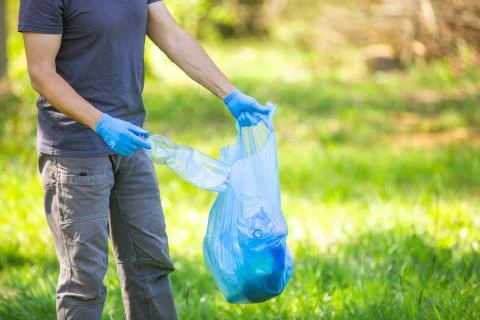 Plastic planet, man picking up plastic bottle, garbage collecting in a forest 写真素材