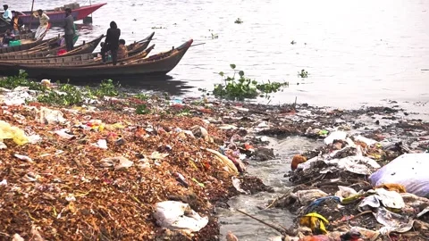 Plastic Pollution And Garbage Waste Piled On River Bank With Wooden Boats Stock Footage 344085880