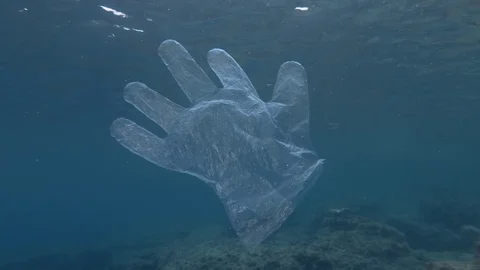 Plastic pollution, Discarded plastic glove slowly drifting under surface of blue Stock Footage 125652604