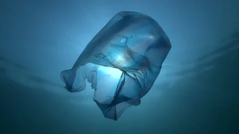 Plastic pollution, used blue plastic bag slowly drifting underwater in sunrays Stock Footage 147068710