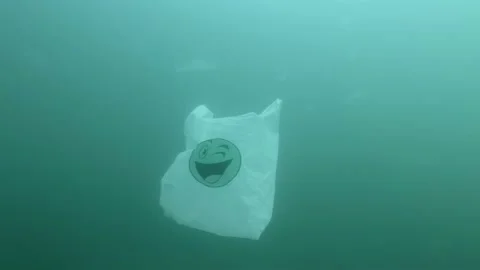 Plastic pollution, used white plastic bag with green smiley slowly drifts Stock Footage 132025268
