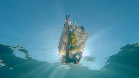 Plastic pollution, used white plastic bag with yellow smiley slowly drifting und Stock Footage 142429739