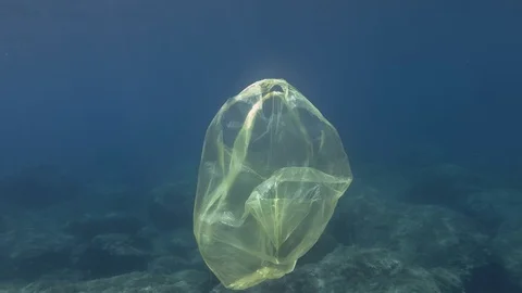 Plastic pollution, Yellow plastic bag in blue water. Discarded plastic bag Stock Footage 114766481