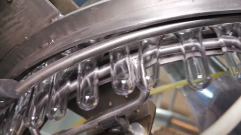 Plastic preform bottles move through the machine for blowing Stock Footage 98719458