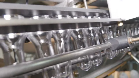 Plastic preform bottles move through the machine for blowing Stock Footage 98720718