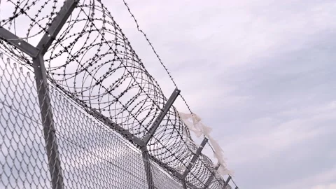 Plastic rags fluttering barbed wire fence on the international border Stock Footage 133274650