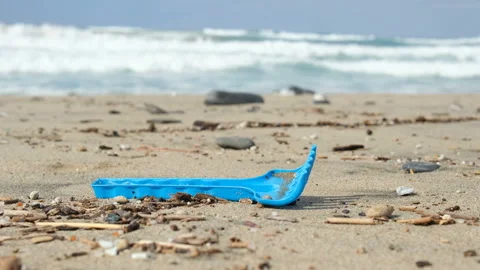 Plastic rake kid beach toy discarded on dirty polluted sea,environment pollution Stock Footage 216527615