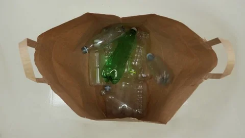 Plastic Recycle Bottles get thrown into a brown bag Video stock 80640888