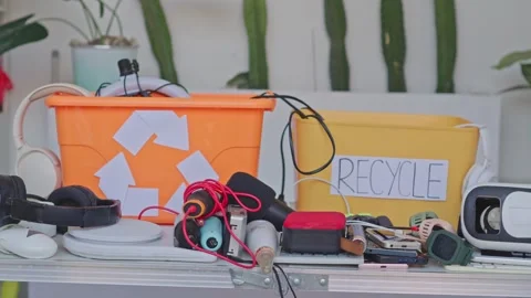 Plastic recycling boxes packed with used electronic devices, headphones, and Stock Footage 340576311