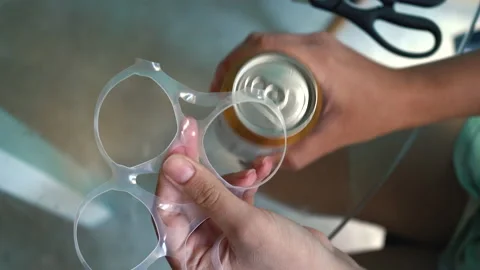Plastic rings for packaging beer female hands are removed from the iron can. Stock Footage 170166972