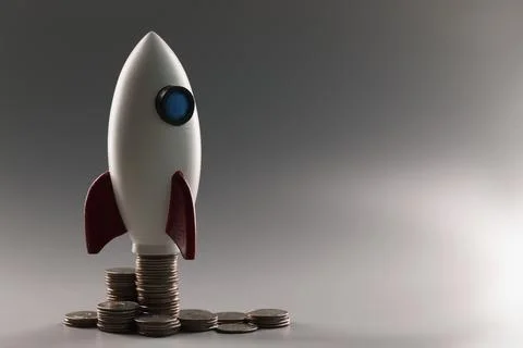 Plastic rocket on top of a stack of coins, close-up 스톡 사진