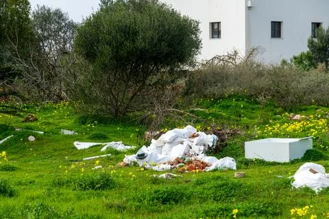Plastic Sacks and Rubble on Grassy Field Near Building Stock Photos