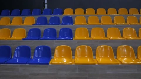 Plastic seats in yellow and blue color on the wooden podium of the stadium Stock Footage 233127944