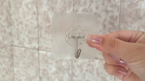 Plastic self-adhesive towel hooks in a womans hand on the background of bathroom Stock Footage 315152874