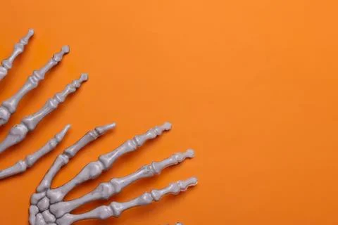 Plastic skeleton hand on orange background for halloween or decor Stock Photos
