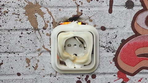 The plastic socket on the wall melts from the overvoltage and lights up.  Video stock 153796066
