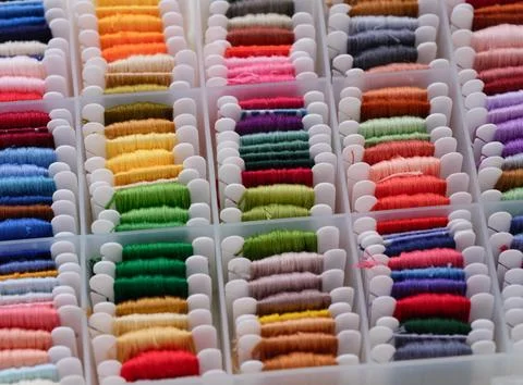 Plastic sorting box full of bobbins with different colour embroidery threads. Stock Photos