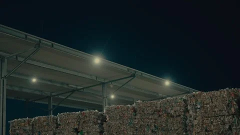 Plastic Sorting Facility Exterior with Bales of Recyclable Waste at Night 库存影片 331166682