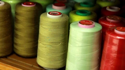 Plastic spools of cotton multicolor thread on sewing machine spindle, close-up Stock Footage 88381718