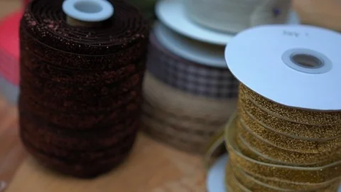 Plastic spools with multicolor fabric ribbon rolls for presents, close-up  库存影片 89240605