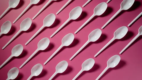 Plastic spoon. Disposable cutlery being put on a pink background in order Видео 133229361