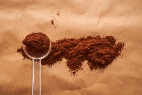 Plastic spoon with ground coffee in the shape of a rectangle on a brown backg Stock Photos