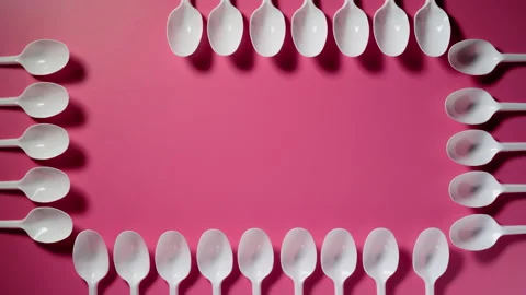 Plastic spoons making a frame on a pink background. Stop motion animation Stock Footage 133229297