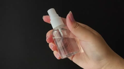 A plastic spray bottle with a milliliter mark in a womans hand on a black Stock Footage 314975255