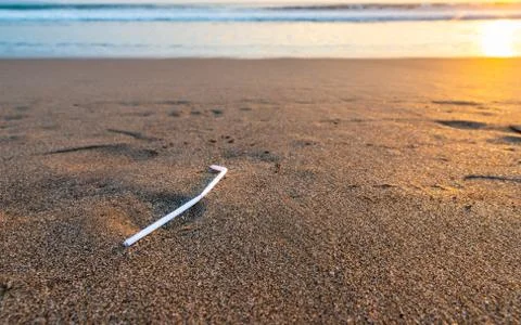 Plastic straw on a beach at sunset Stock Photos