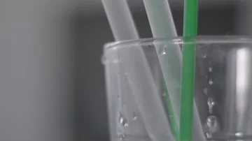 Plastic straws being removed and placed back into a glass in slow motion Stock Footage 85836695