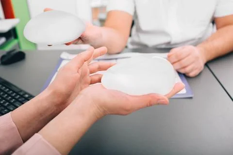 Plastic surgeon demonstrates breast implants to a patient for her new breast. Фото