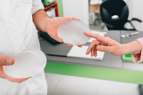 Plastic surgeon demonstrates breast implants to a patient for her new breast. Photos