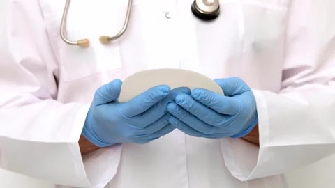 Plastic surgeon demonstrating the flexibility and texture of a breast implant du Stock Footage 342615539