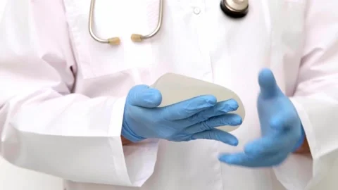 Plastic surgeon holding a textured silicone breast implant for augmentation mamm Stock Footage 342615545