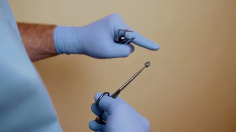 A plastic surgeon holds instruments in his hands before surgery. The doctor Stock Footage 142336638