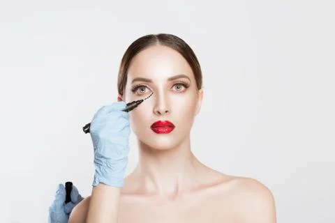Plastic surgery concept. Doctor Hands drawing marks on female face against wh Stock Photos