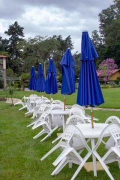 Plastic table and chairs with closed umbrellas on each one Stock Photos
