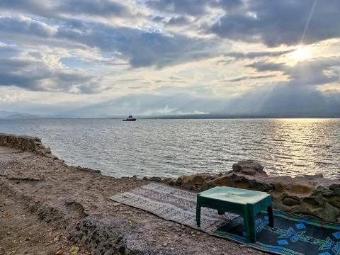 A plastic table with a mat on the beach. Sunset and silhouette Stock Photos