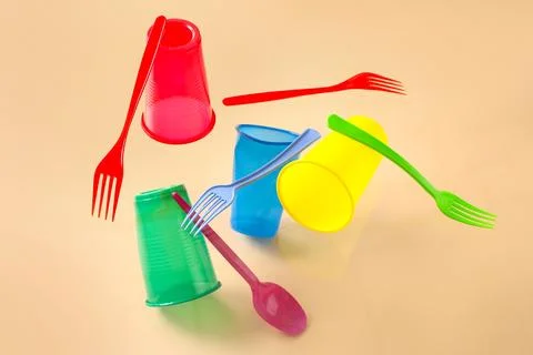 Plastic tableware levitating on beige background Stock Photos