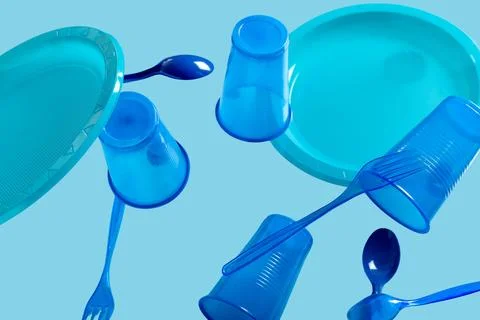 Plastic tableware levitating on blue background Stock Photos