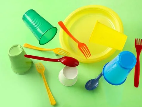 Plastic tableware levitating on green background Stock Photos