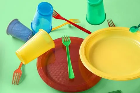 Plastic tableware levitating on green background Stock Photos