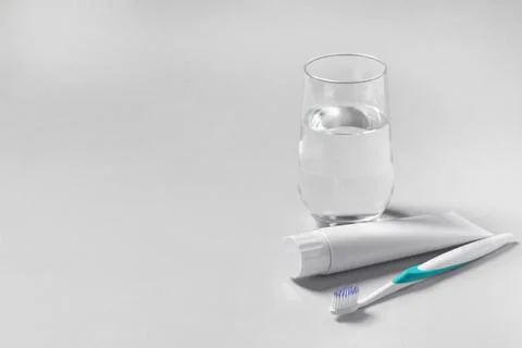 Plastic toothbrush with paste and glass of water on grey background, space .. Foto stock