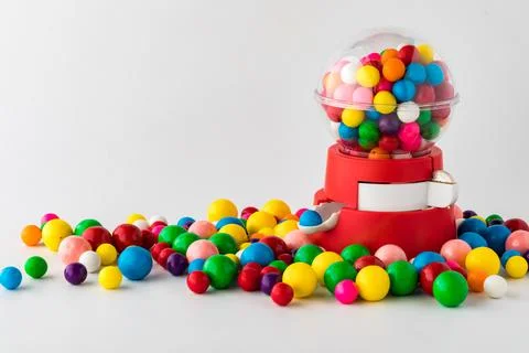 A plastic toy gum ball machine with colourful gum balls all around. Stock Photos