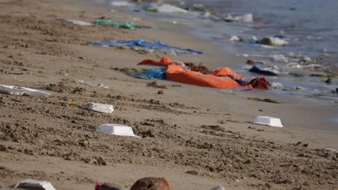 Plastic trash and containers litter a sandy beach beside the waterline. Polluted Stock Footage 345700501