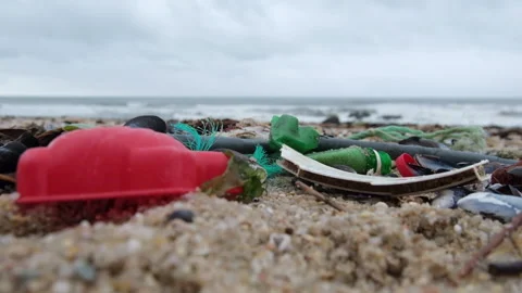 Plastic trash on the beach. Shallow depth of field, slow motion. Видео 145625922